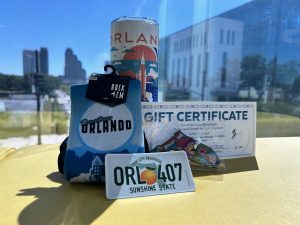 City of Orlando Package that includes an Orlando Sticker, Florida shaped magnet, socks with Lake Eola fountain, an orlando themed cup, and a gift certificate for Lake Eola Swan Boats