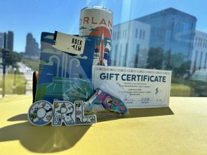 City of Orlando Package that includes an Orlando Sticker, Florida shaped magnet, socks with Lake Eola fountain, an orlando themed cup, and a gift certificate for Lake Eola Swan Boats