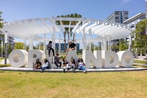 Students sitting on Luminary Park Orlando sign